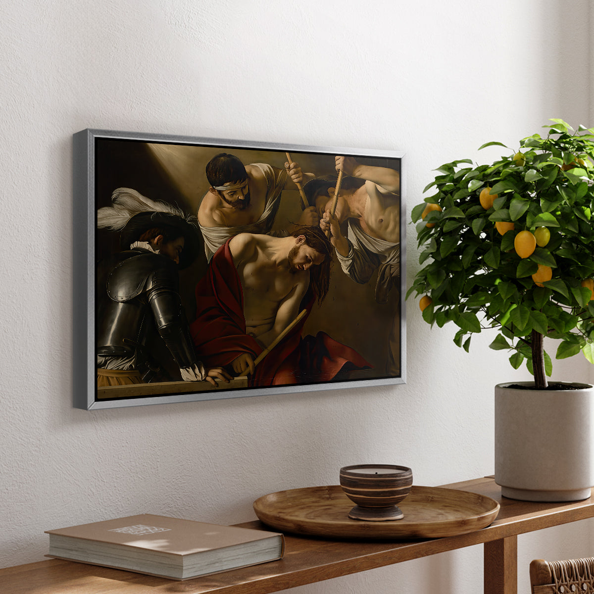 The Crowning with Thorns (Vienna Version), c. 1602-1604 by Caravaggio, presented in a silver floater framed canvas featuring Christ surrounded by men pressing crown of thorns onto his head, displayed above a hallway console table.