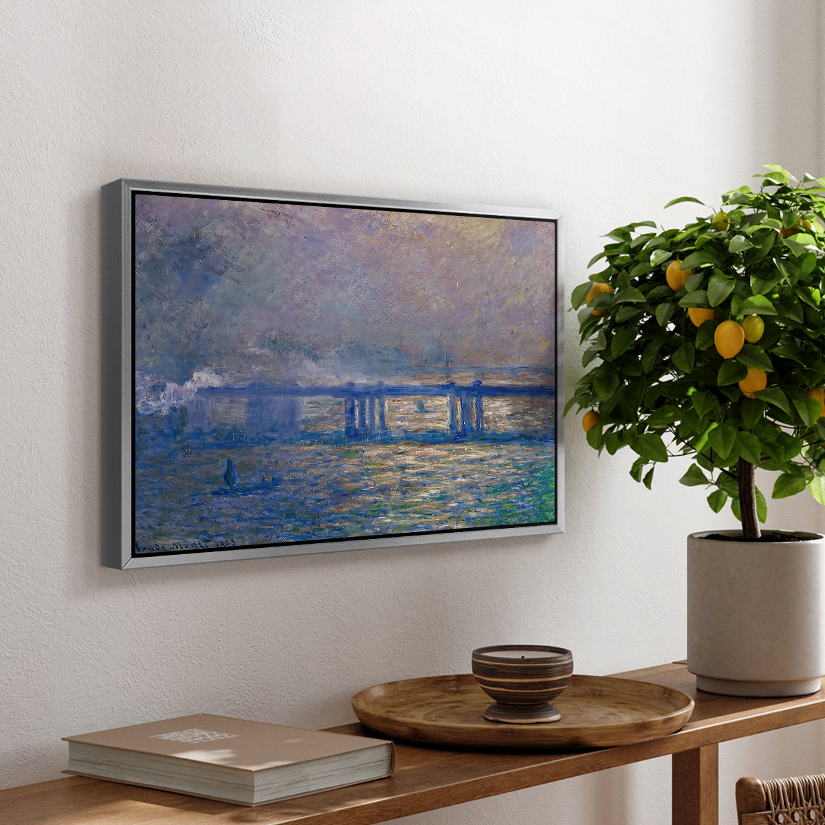 Charing Cross Bridge, 1903 by Claude Monet, presented in a silver floater framed canvas featuring an impressionist view of bridge stretching across river with soft light and haze, displayed above a hallway console table.