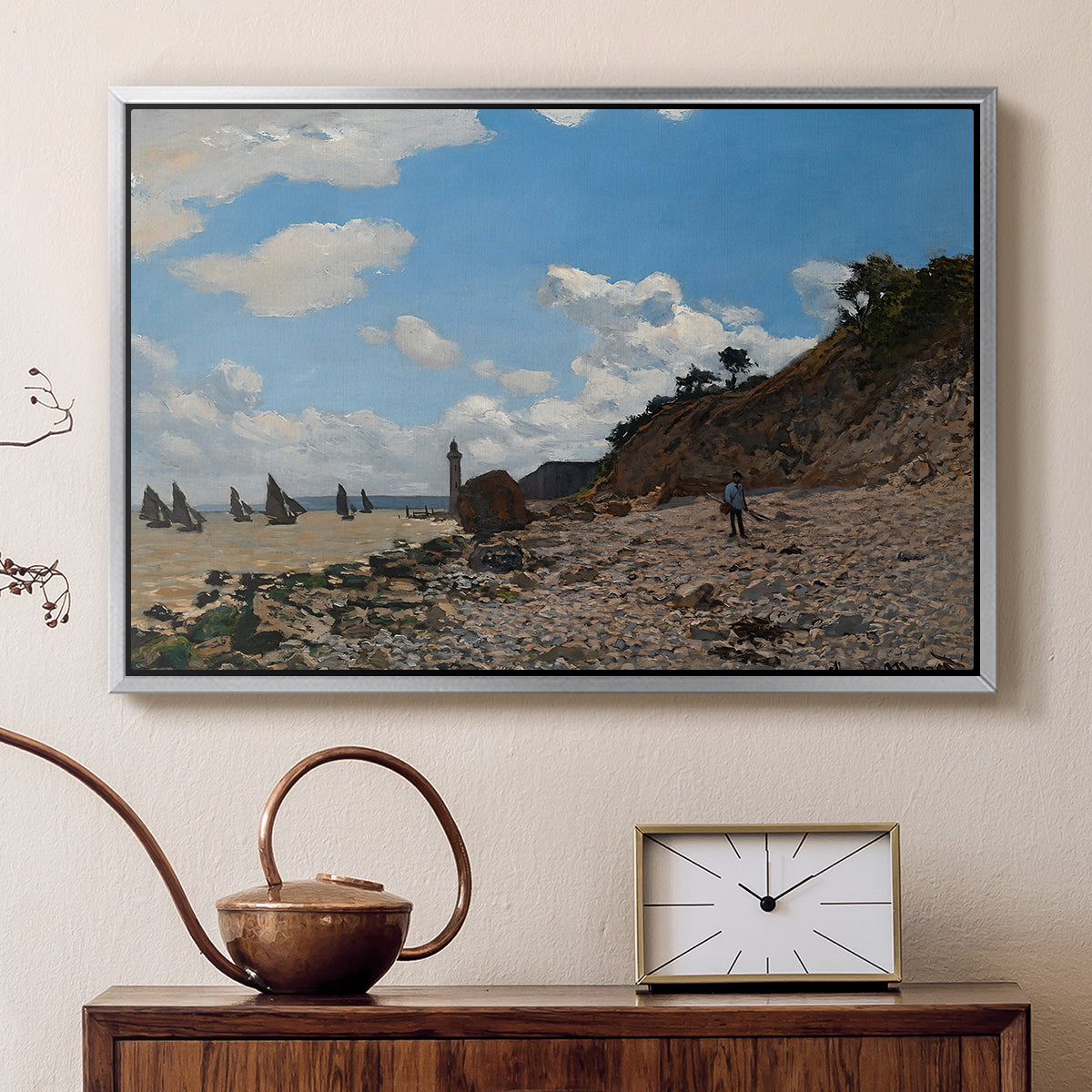 Silver floater framed canvas featuring a sandy beach with figures relaxing near water's edge, displayed above a cabinet in a soft-toned living room.