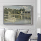 The Bridge at Argenteuil, 1874 by Claude Monet displayed above a sofa in a living room in a silver floater frame, featuring an impressionist river scene with boats passing beneath bridge.