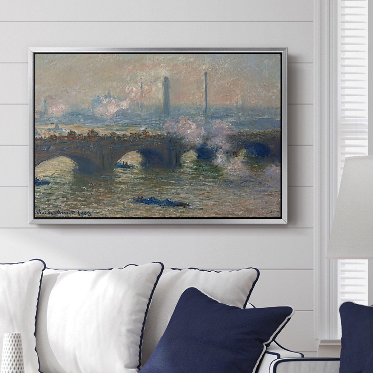 Waterloo Bridge, Gray Day, 1903 by Claude Monet displayed above a sofa in a living room in a silver floater frame, featuring an impressionist depiction of bridge with soft gray tones and haze.