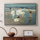 Silver floater framed canvas featuring an impressionist coastal view of families enjoying seaside water, displayed above a cabinet in a soft-toned living room.