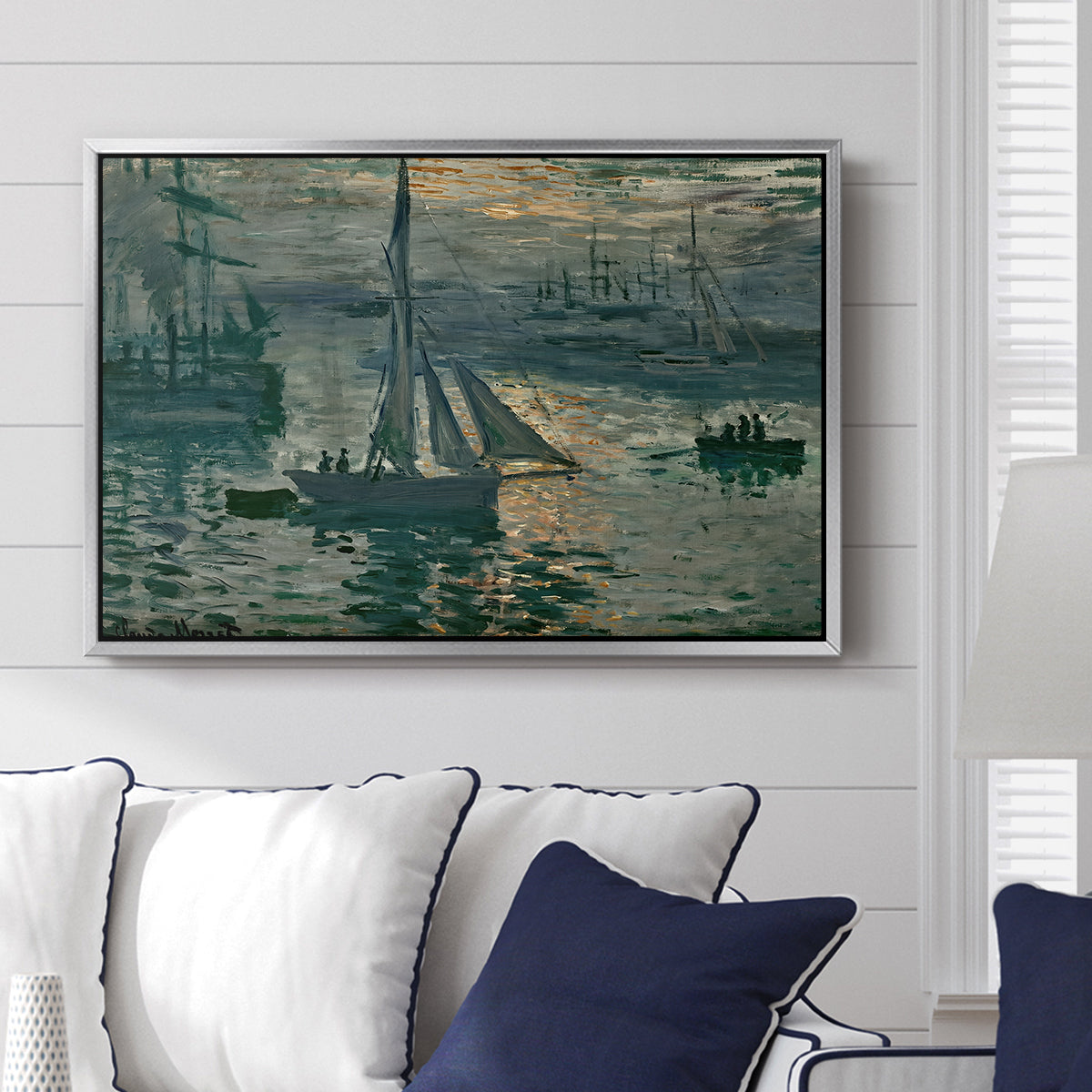 Sunrise (Marine), 1873 by Claude Monet displayed above a sofa in a living room in a silver floater frame, featuring an impressionist seascape with glowing sun and misty water.