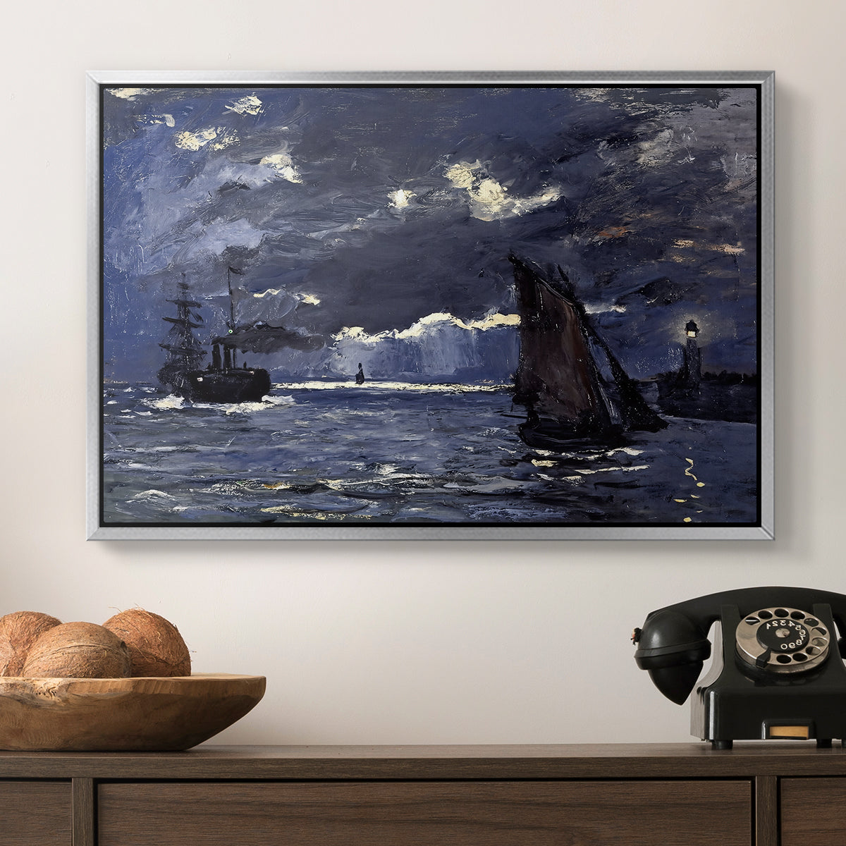 A Seascape, Shipping by Moonlight, 1864 by Claude Monet in a silver floater framed canvas displayed above a console table in a hallway, featuring an atmospheric maritime view with ships in moonlit darkness.