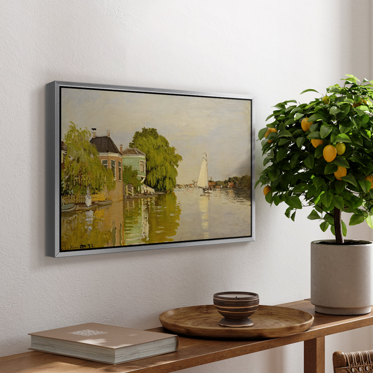 Houses on the Achterzaan, 1871 by Claude Monet, presented in a silver floater framed canvas featuring colorful houses reflected in calm river surrounded by greenery, displayed above a hallway console table.