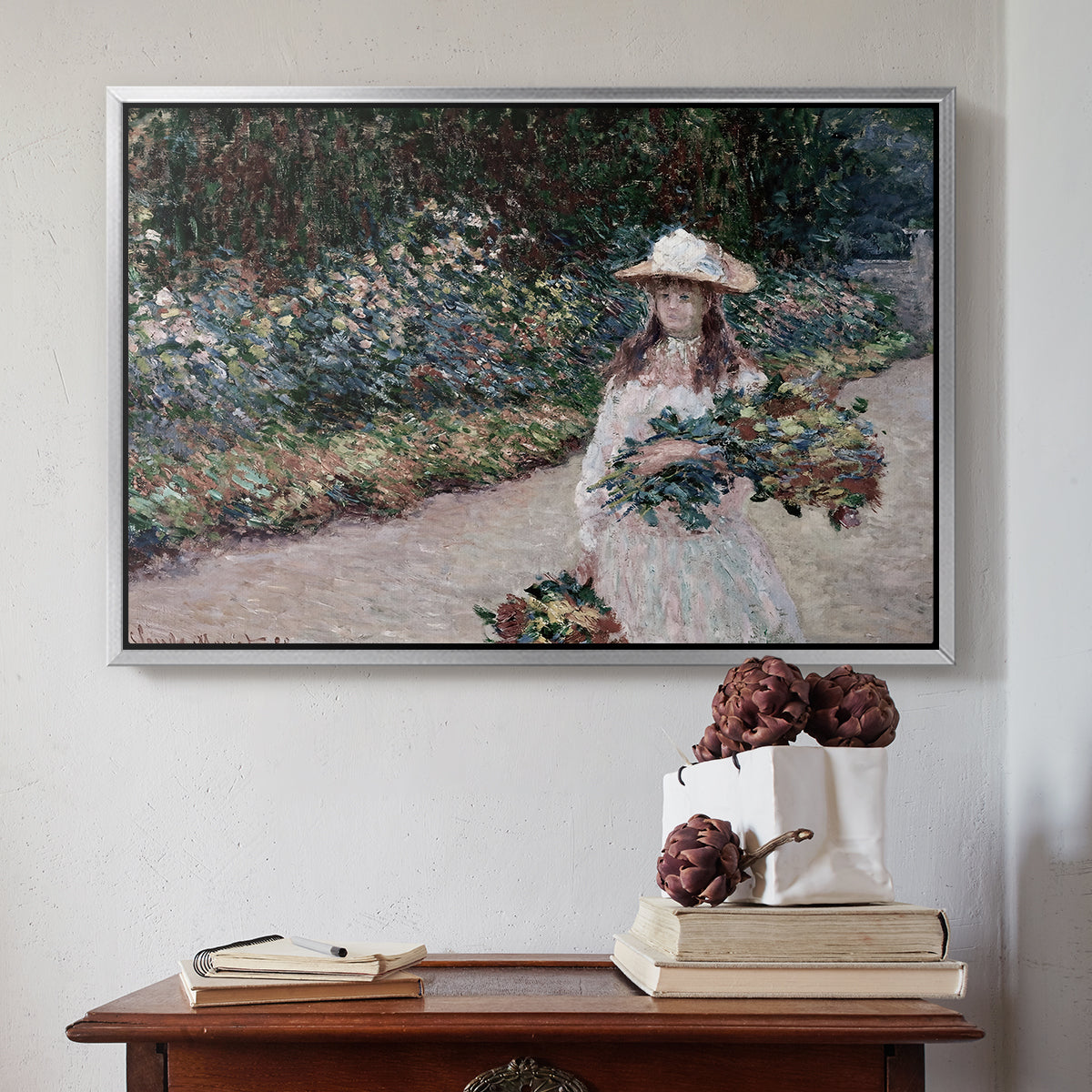 Silver floater framed canvas featuring Young Girl in the Garden at Giverny, 1888 by Claude Monet above an entryway table in a minimalist foyer.