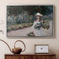 Silver floater framed canvas featuring a figure resting in colorful garden under soft light, displayed above a cabinet in a soft-toned living room.
