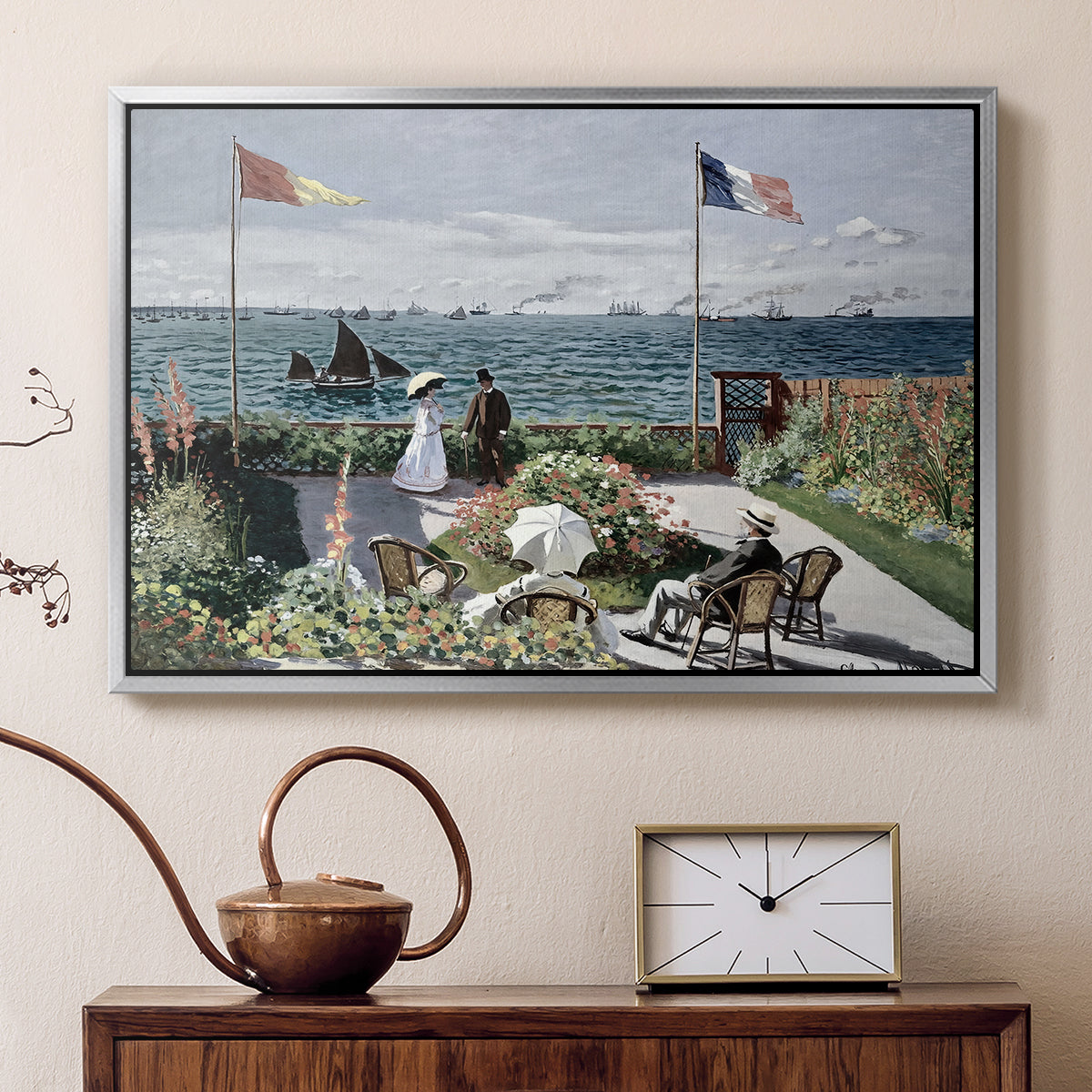 Silver floater framed canvas featuring a vibrant garden scene with colorful blooms and distant sea, displayed above a cabinet in a soft-toned living room.