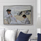On the Beach at Trouville, 1870 by Claude Monet displayed above a sofa in a living room in a silver floater frame, featuring an impressionist seaside scene with women in dresses and hats.