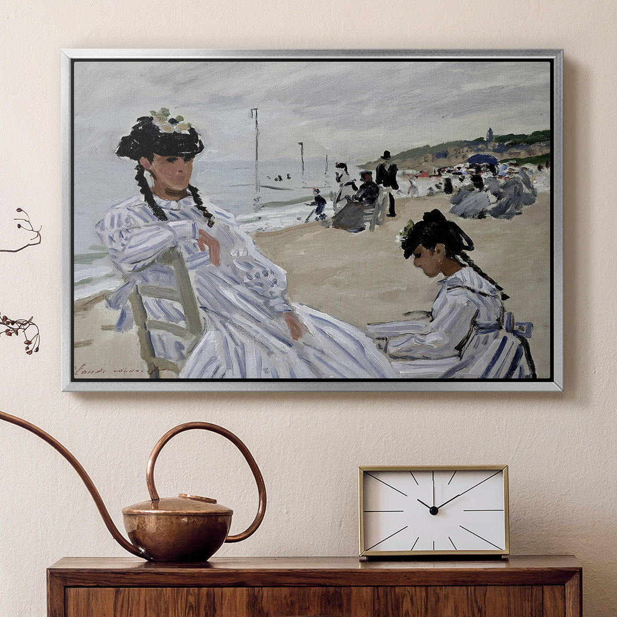 Silver floater framed canvas featuring a beach setting with people relaxing under umbrellas, displayed above a cabinet in a soft-toned living room.