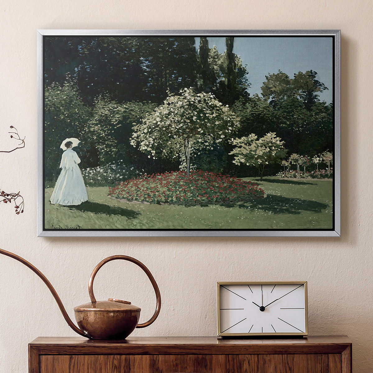 Silver floater framed canvas featuring an elegant woman posed outdoors among blooming plants, displayed above a cabinet in a soft-toned living room.