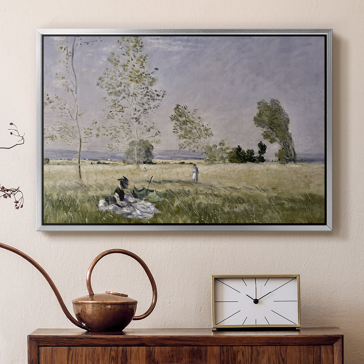 Silver floater framed canvas featuring a sunlit meadow with woman surrounded by greenery, displayed above a cabinet in a soft-toned living room.