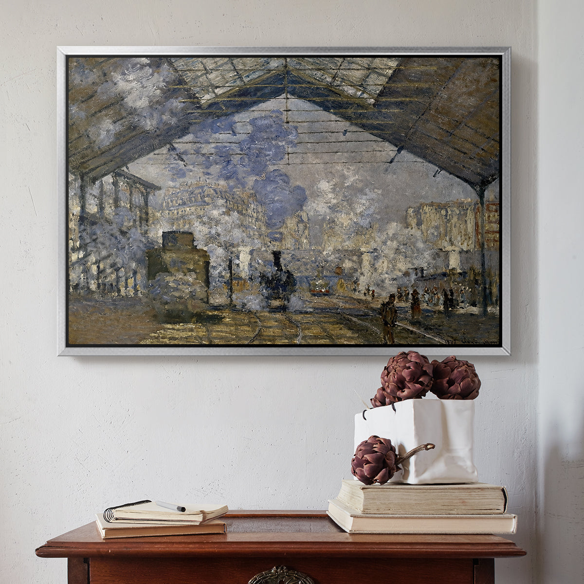 Silver floater framed canvas featuring The Gare Saint-Lazare, 1877 by Claude Monet above an entryway table in a minimalist foyer.