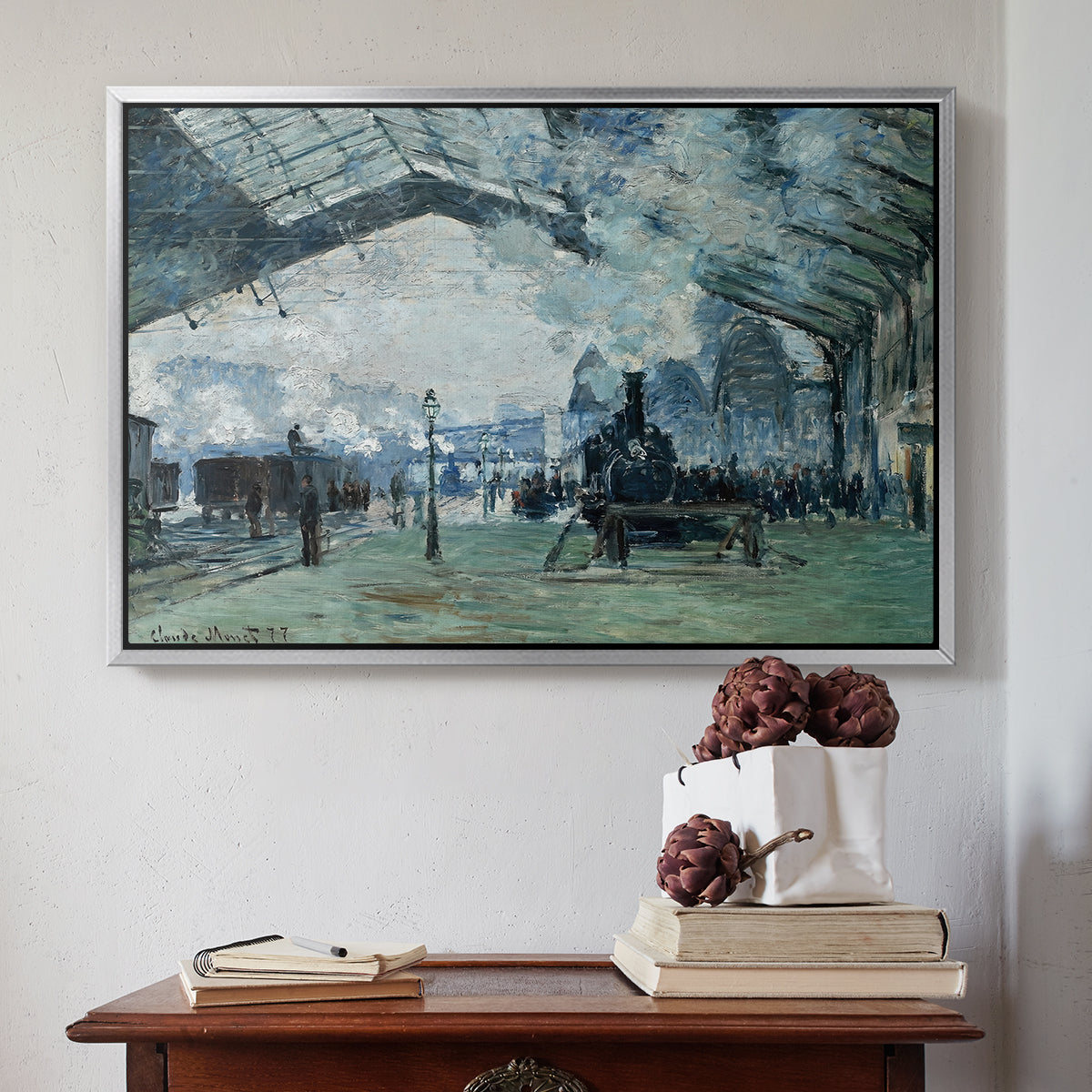 Silver floater framed canvas featuring The Saint-Lazare Station, 1877 by Claude Monet above an entryway table in a minimalist foyer.
