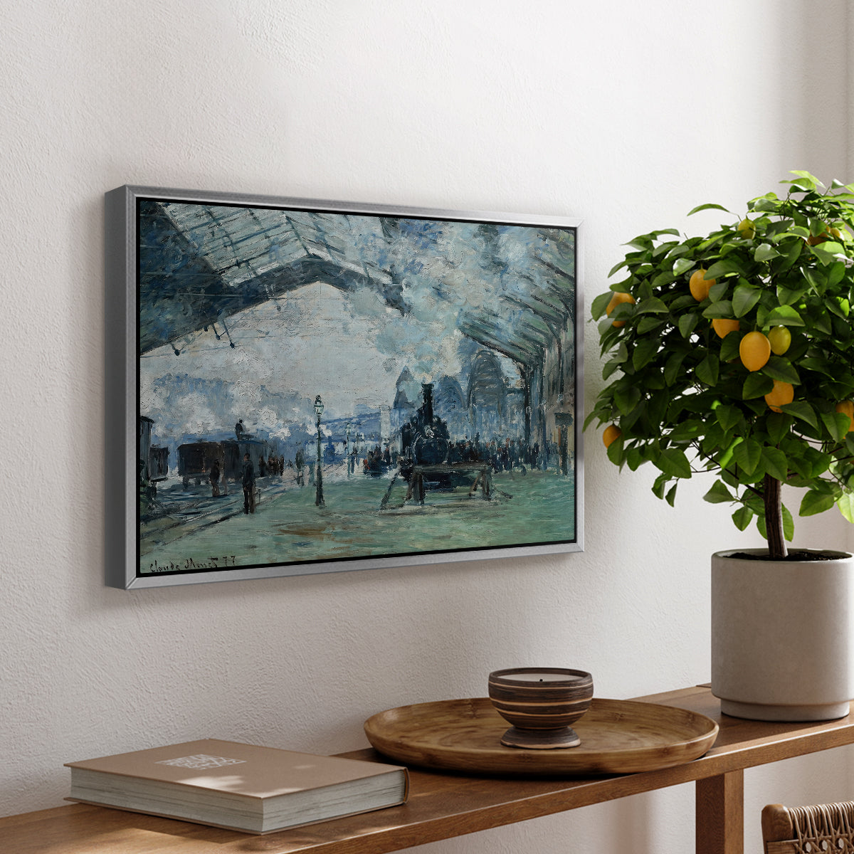The Saint-Lazare Station, 1877 by Claude Monet, presented in a silver floater framed canvas featuring trains arriving under large arched station roof with billowing steam, displayed above a hallway console table.