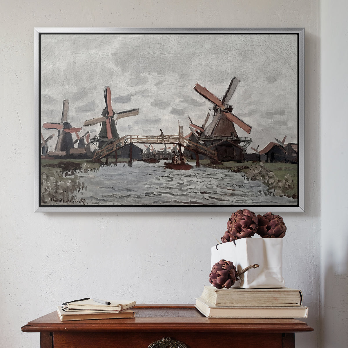 Silver floater framed canvas featuring Windmills near Zaandam, 1871 by Claude Monet above an entryway table in a minimalist foyer.