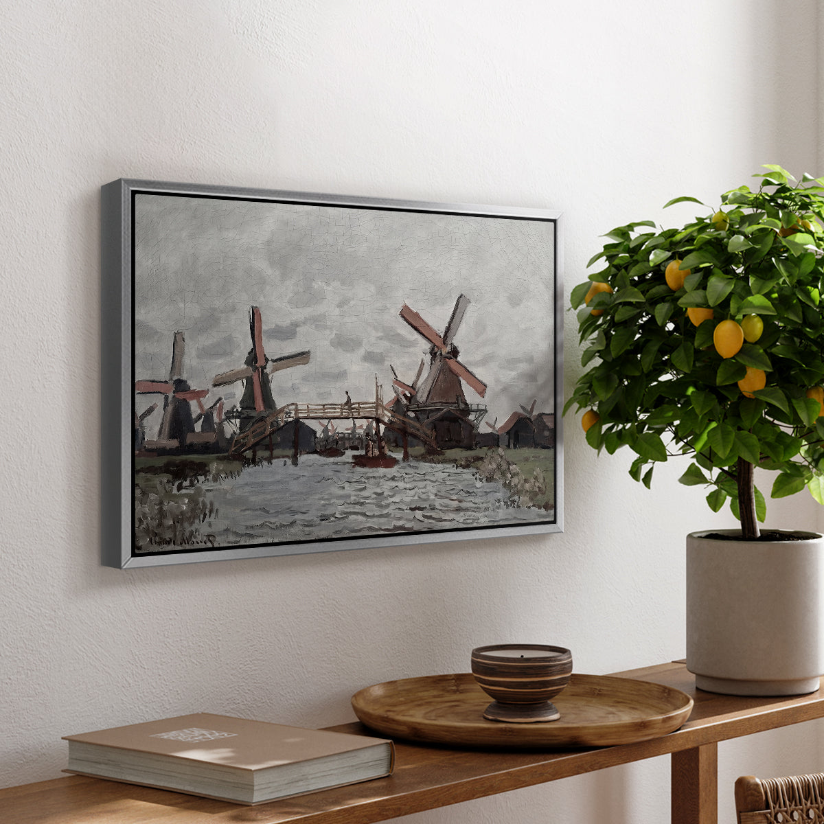 Windmills near Zaandam, 1871 by Claude Monet, presented in a silver floater framed canvas featuring windmills standing beside water under open sky in rural landscape, displayed above a hallway console table.