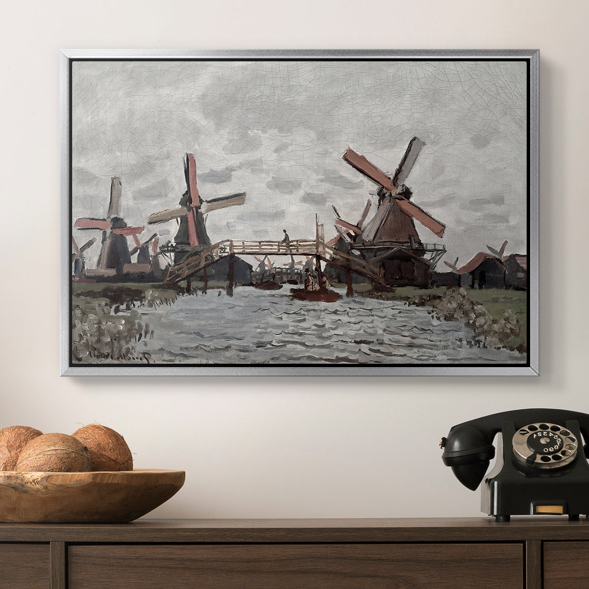Windmills near Zaandam, 1871 by Claude Monet in a silver floater framed canvas displayed above a console table in a hallway, featuring a landscape featuring windmills and low horizon sky.