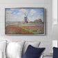 Tulip Fields with the Rijnsburg Windmill, 1886 by Claude Monet displayed above a sofa in a living room in a silver floater frame, featuring a vibrant agricultural landscape with flowers and windmill.