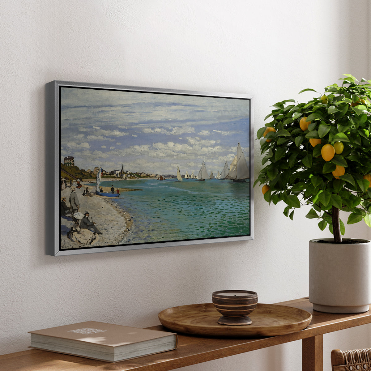 Regatta at Sainte-Adresse, 1867 by Claude Monet, presented in a silver floater framed canvas featuring sailboats gathered near shore with flags and spectators along coastline, displayed above a hallway console table.