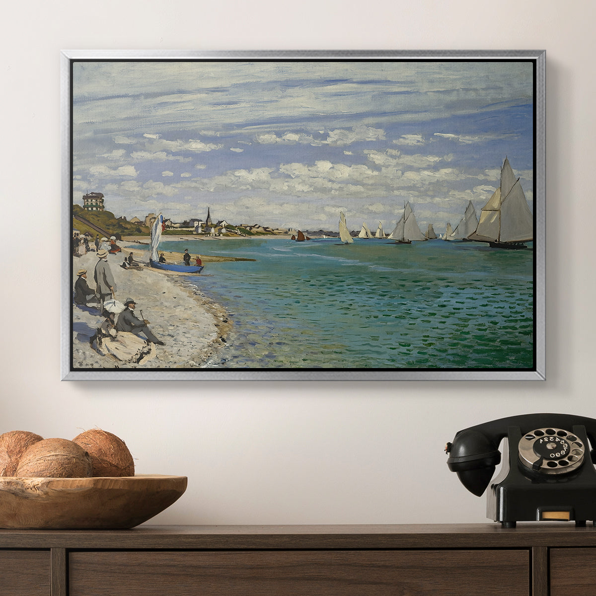 Regatta at Sainte-Adresse, 1867 by Claude Monet in a silver floater framed canvas displayed above a console table in a hallway, featuring a nautical scene with boats racing near seaside town.