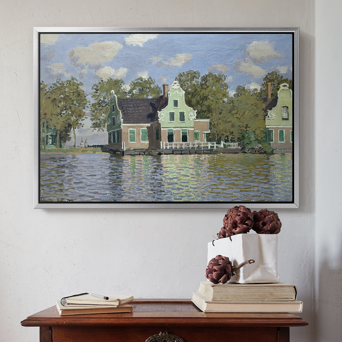 Silver floater framed canvas featuring Houses on the Zaan River at Zaandam, 1871 by Claude Monet above an entryway table in a minimalist foyer.