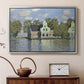 Silver floater framed canvas featuring a peaceful canal scene with houses mirrored in water, displayed above a cabinet in a soft-toned living room.
