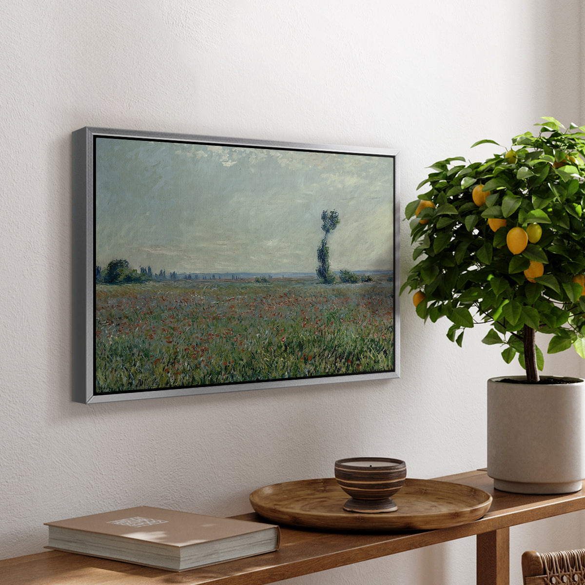 Poppy Field, 1881 by Claude Monet, presented in a silver floater framed canvas featuring a wide field of red poppies stretching across countryside under open sky, displayed above a hallway console table.