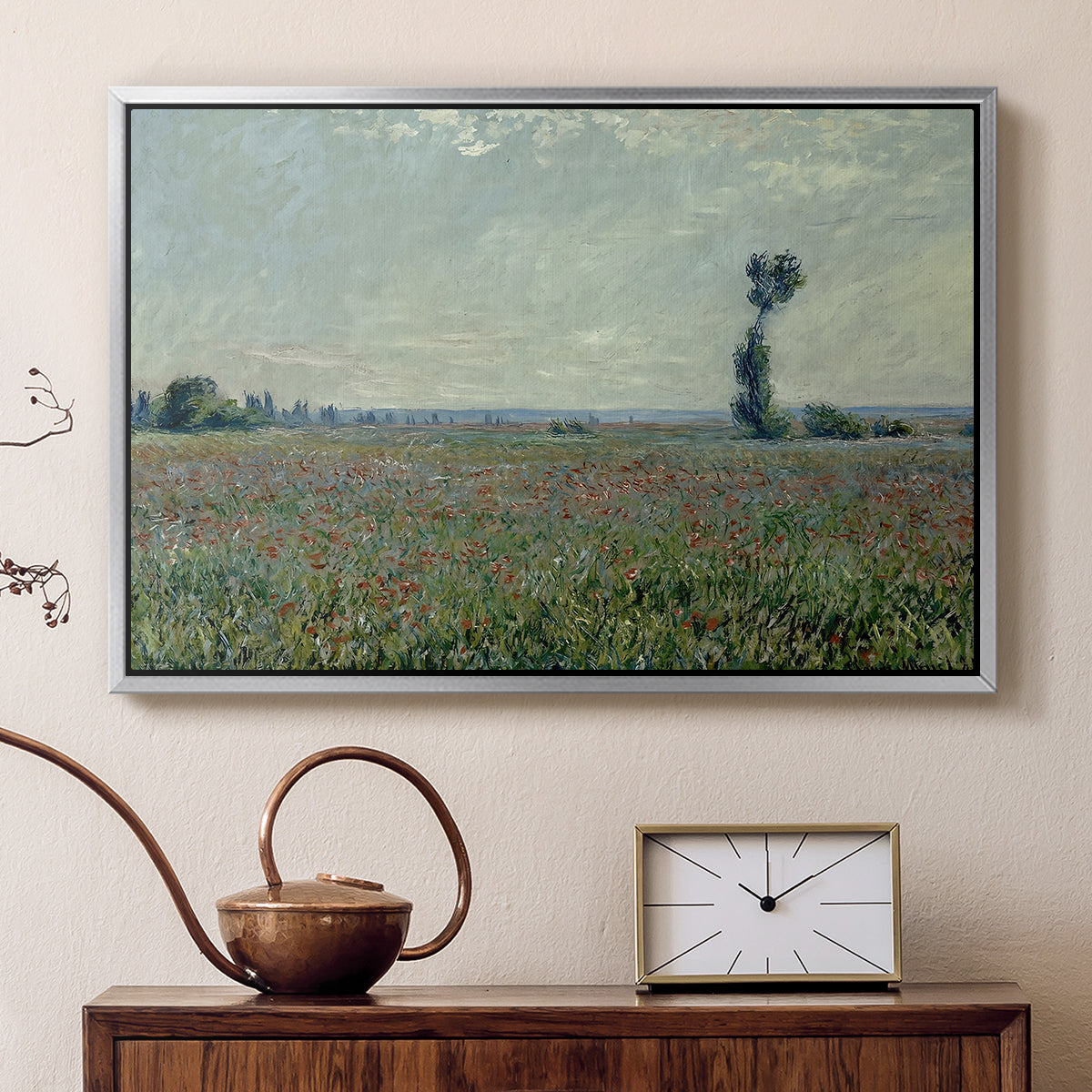 Silver floater framed canvas featuring a rural meadow with scattered poppies and soft horizon, displayed above a cabinet in a soft-toned living room.