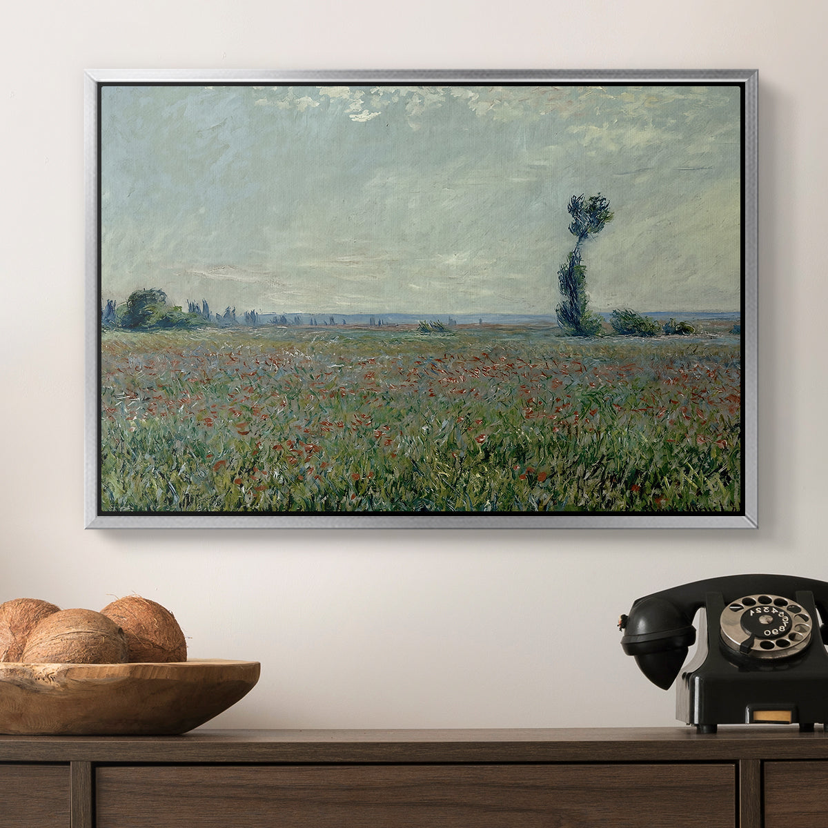 Poppy Field, 1881 by Claude Monet in a silver floater framed canvas displayed above a console table in a hallway, featuring a natural field scene with vibrant red flowers.