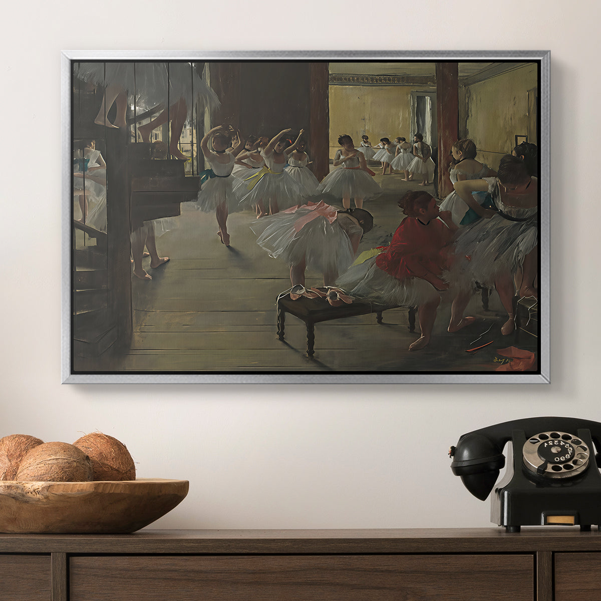 The Dance Class, c. 1873 by Edgar Degas in a silver floater framed canvas displayed above a console table in a hallway, featuring a group of dancers preparing during class with natural light.