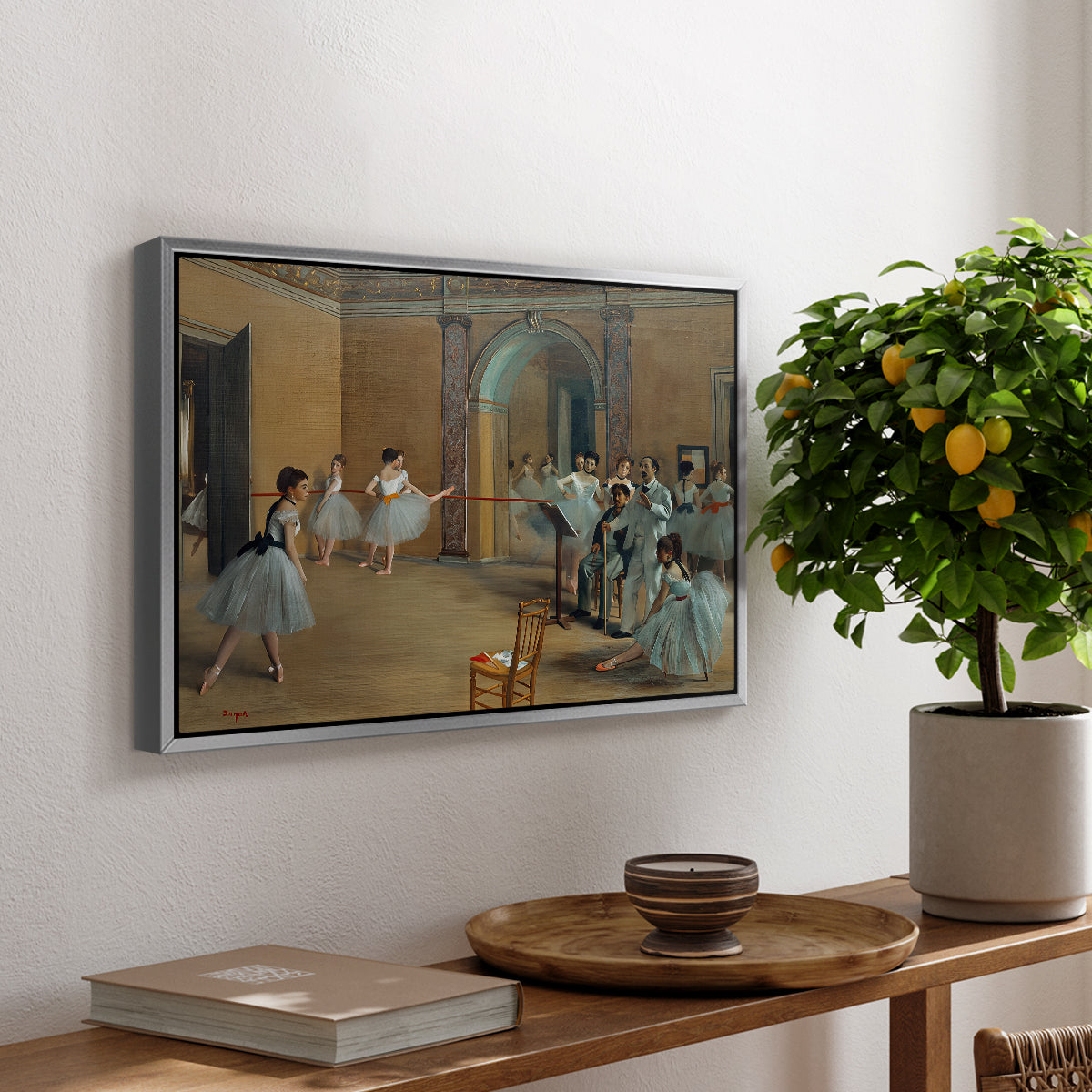 The Dance Foyer at the Opera on the Rue Le Peletier, 1872 by Edgar Degas, presented in a silver floater framed canvas featuring ballet dancers gathered in rehearsal hall with mirrors and columns, displayed above a hallway console table.
