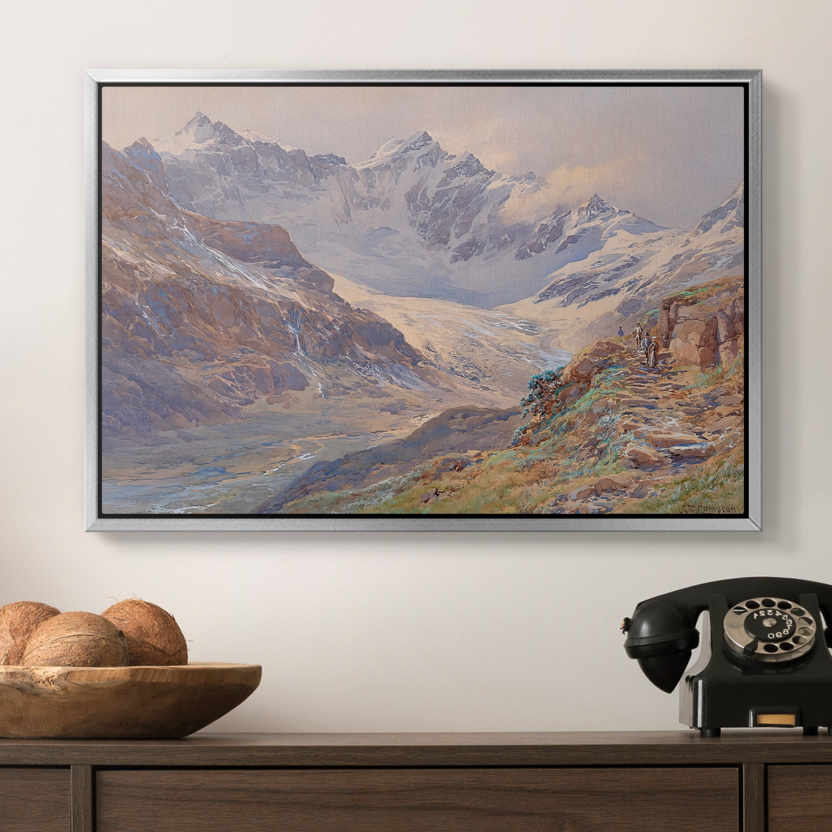 Odenwinklkees with the Johannisberg, 1902 by Edward Theodore Compton in a silver floater framed canvas displayed above a console table in a hallway, featuring an expansive alpine view with ice and distant mountains.