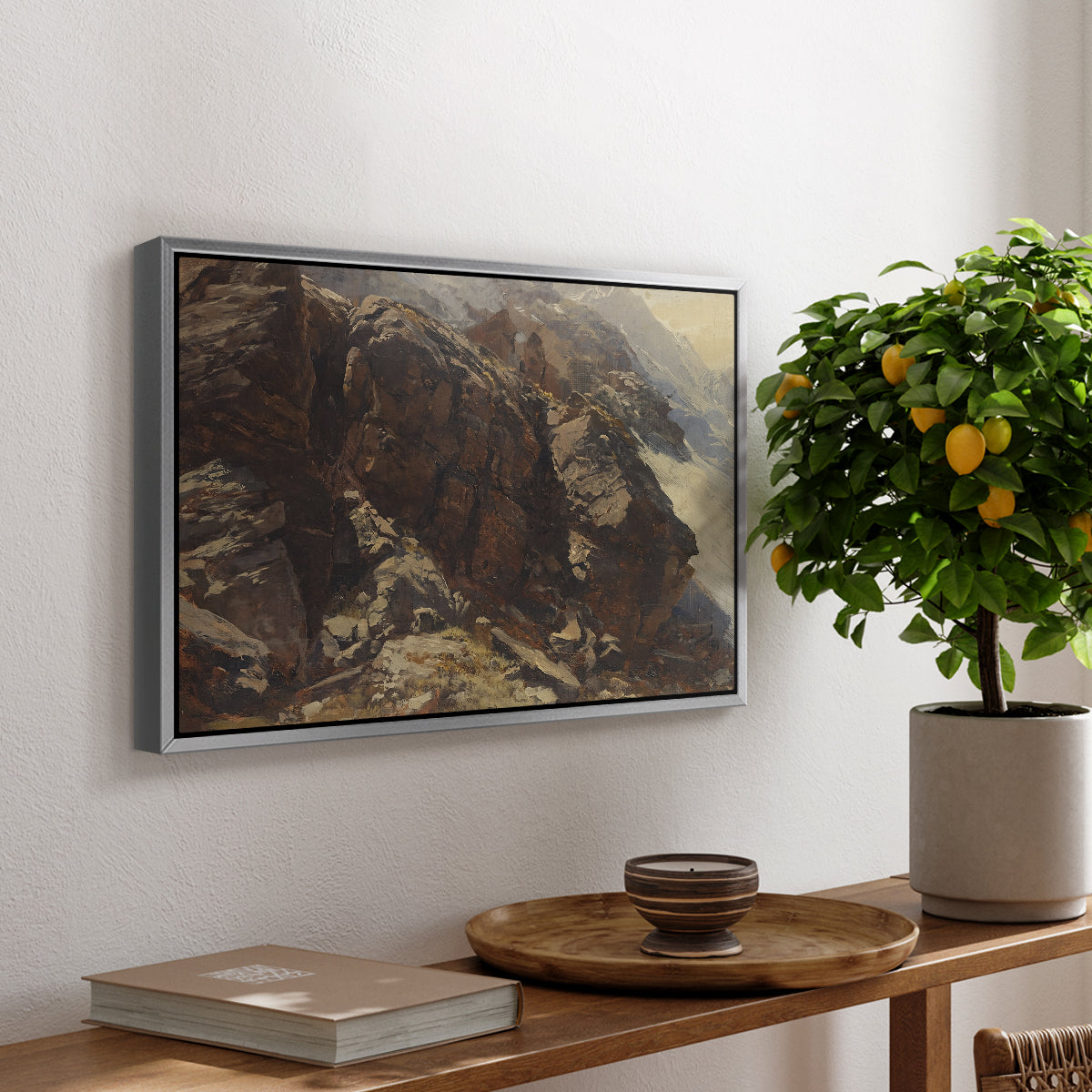 High Mountain Study, c. 1870 by Edward Theodore Compton, presented in a silver floater framed canvas featuring a rocky alpine terrain with steep slopes and distant mountain peaks, displayed above a hallway console table.