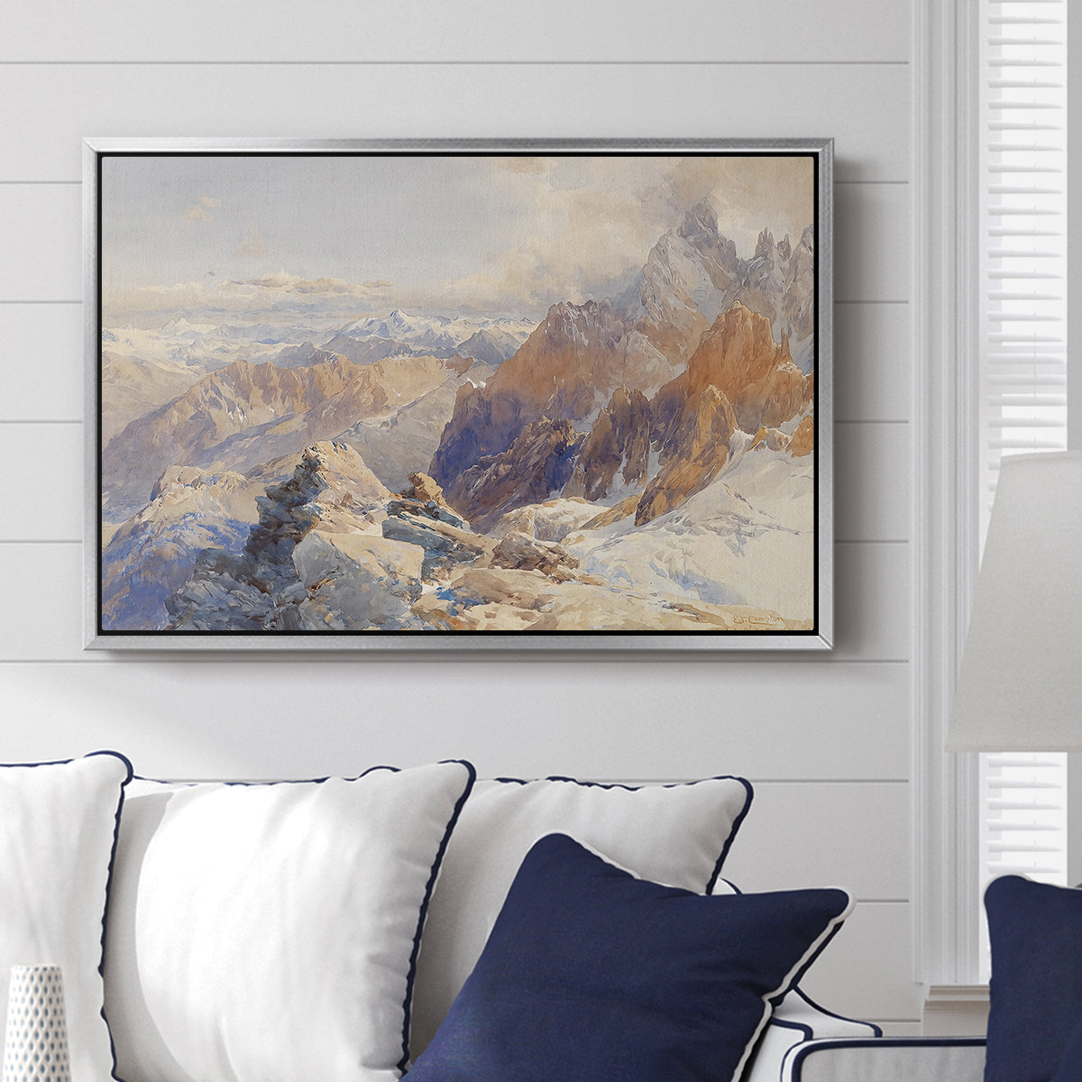 Col du Géant, 1903 by Edward Theodore Compton displayed above a sofa in a living room in a silver floater frame, featuring a high mountain landscape featuring dramatic ridges and glacier terrain.