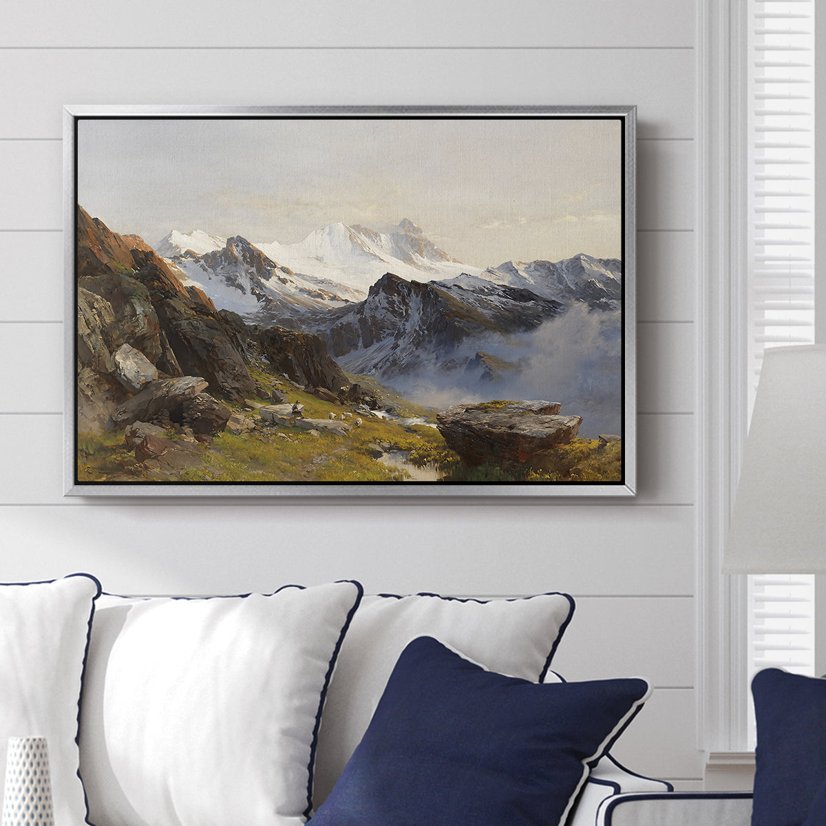 The Großglockner from the Prager Hut, 1890 by Edward Theodore Compton displayed above a sofa in a living room in a silver floater frame, featuring a mountain summit seen from elevated viewpoint with surrounding landscape.