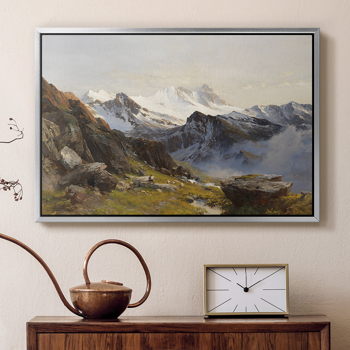 Silver floater framed canvas featuring an alpine vista with towering peak and foreground terrain, displayed above a cabinet in a soft-toned living room.