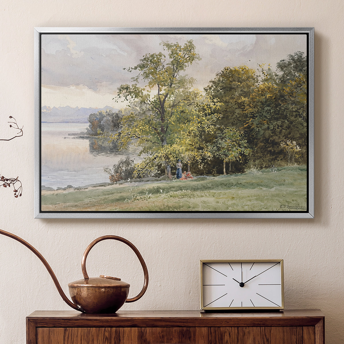 Silver floater framed canvas featuring a natural setting with water, trees, and open sky, displayed above a cabinet in a soft-toned living room.