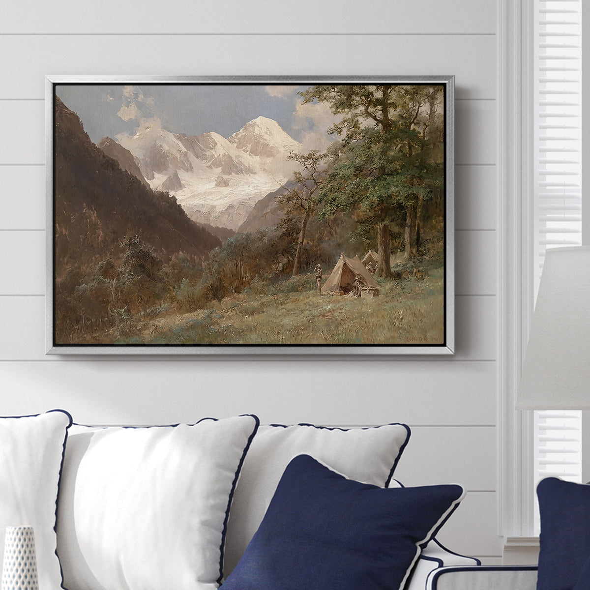Landscape in the Caucasus, c. 1921 by Edward Theodore Compton displayed above a sofa in a living room in a silver floater frame, featuring an expansive view of Caucasus mountains under open sky.