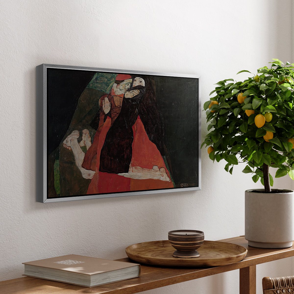 Cardinal and Nun (Caress), 1912 by Egon Schiele, presented in a silver floater framed canvas featuring two figures embracing intimately in stylized expressionist composition, displayed above a hallway console table.