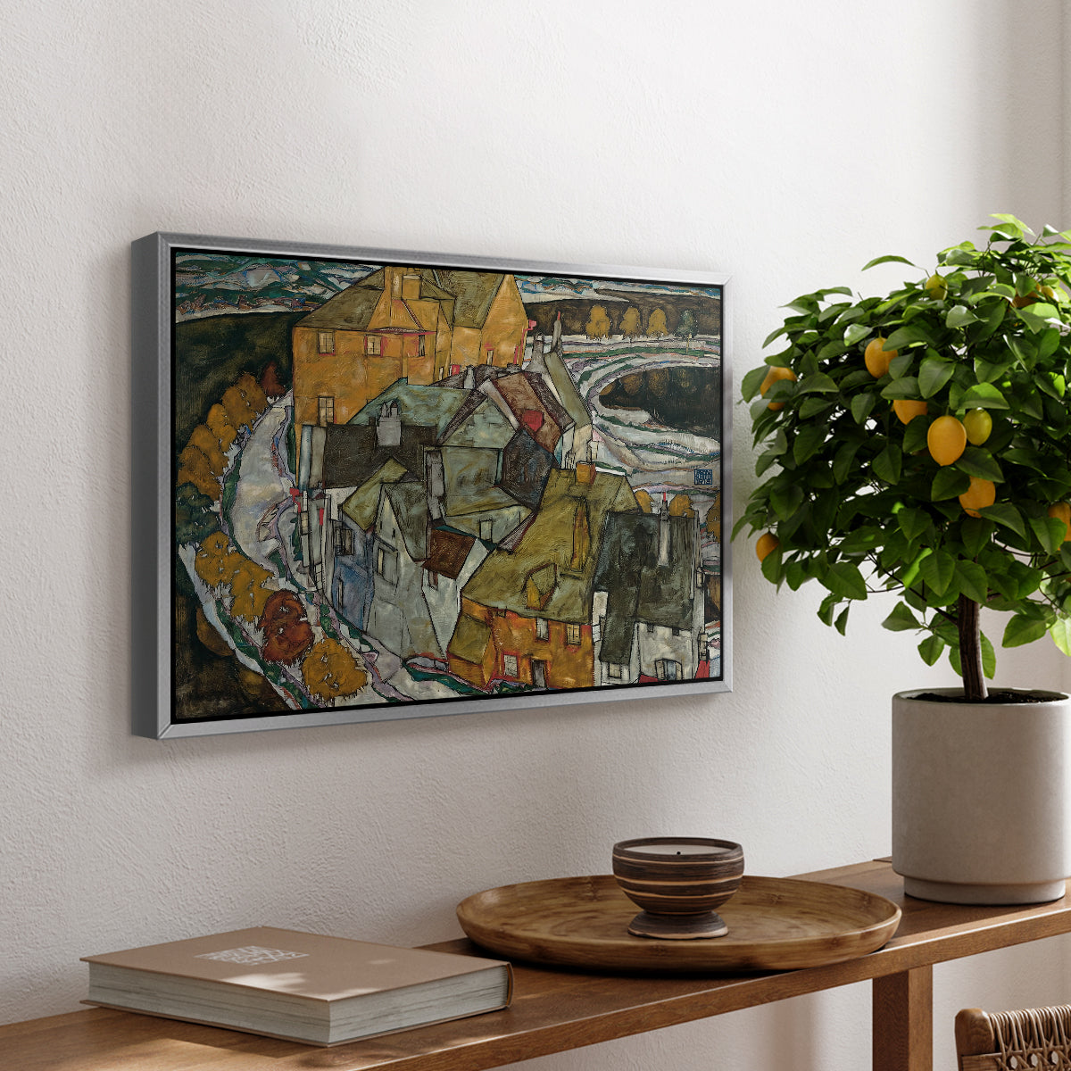 Crescent of Houses II (Island Town), 1915 by Egon Schiele, presented in a silver floater framed canvas featuring a curved row of colorful houses forming crescent shape along water, displayed above a hallway console table.