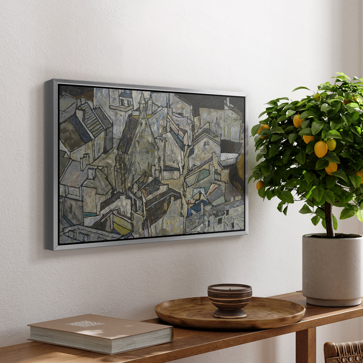 Mödling II, 1918 by Egon Schiele, presented in a silver floater framed canvas featuring clustered geometric houses forming dense urban landscape with sharp angles, displayed above a hallway console table.