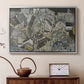 Silver floater framed canvas featuring an abstracted town view with angular rooftops and fragmented forms, displayed above a cabinet in a soft-toned living room.