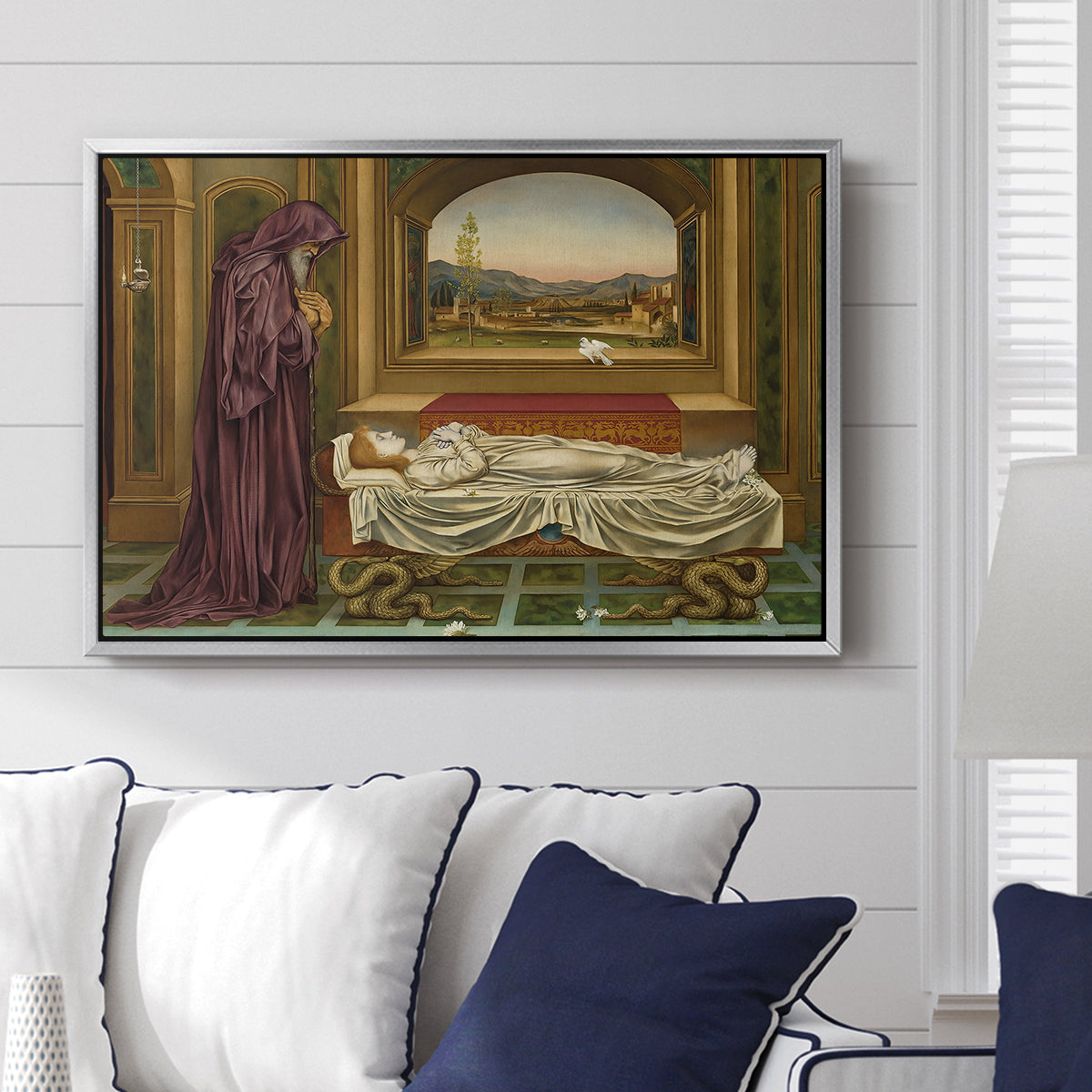 The Wandering Jew: Whom the Gods Love Die Young, 1888 by Evelyn De Morgan displayed above a sofa in a living room in a silver floater frame, featuring a symbolic portrait of wandering figure in quiet architectural setting.