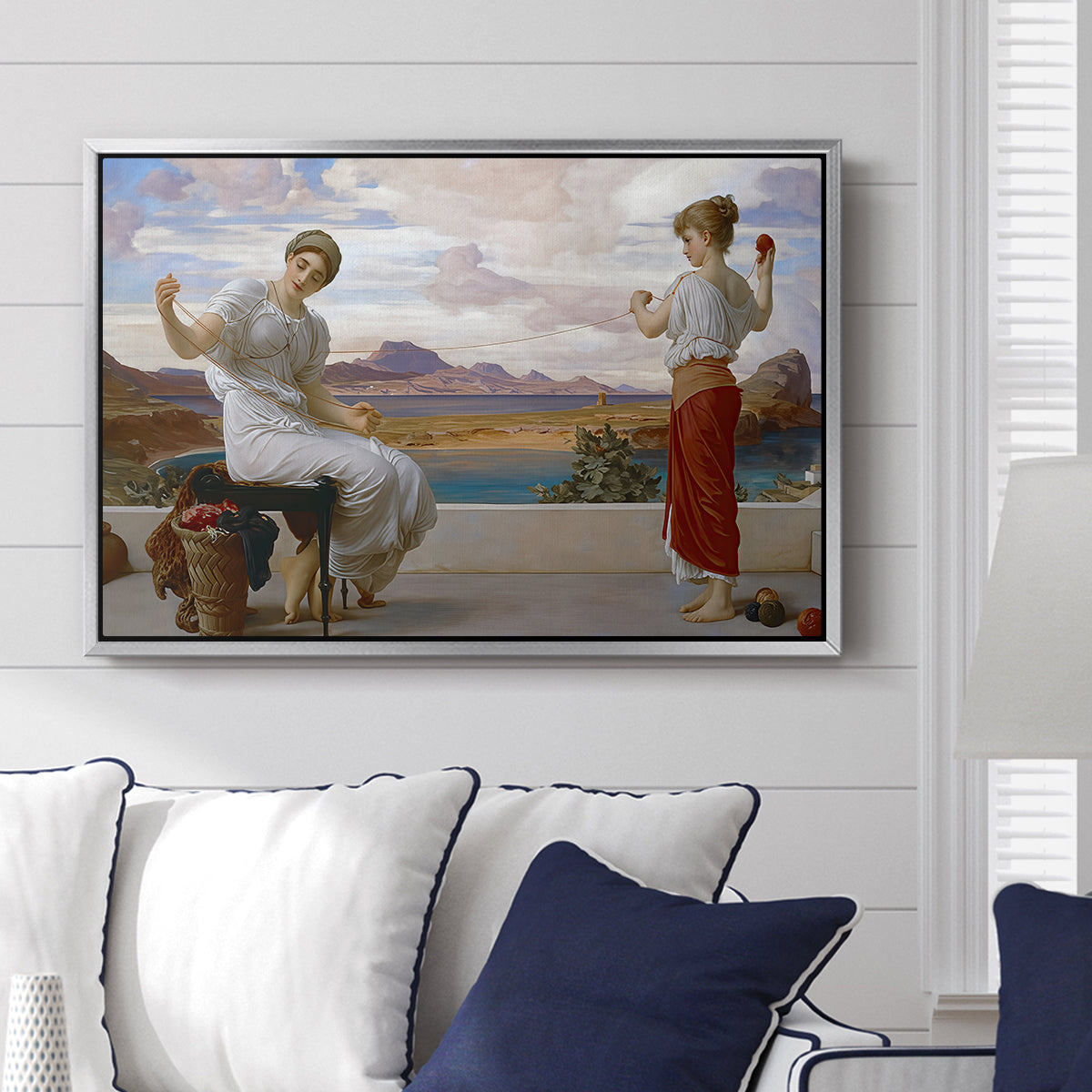 Winding the Skein, c. 1878 by Frederic Leighton displayed above a sofa in a living room in a silver floater frame, featuring two women engaged in textile work with draped garments.