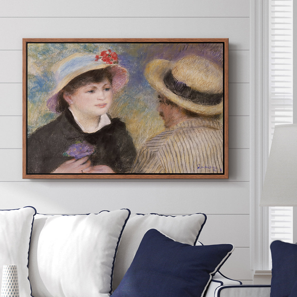 Boating Couple (Aline Charigot and Renoir), c. 1881 by Pierre-Auguste Renoir displayed above a sofa in a living room in a walnut floater frame, featuring an intimate portrait of man and woman sitting side by side in outdoor setting.