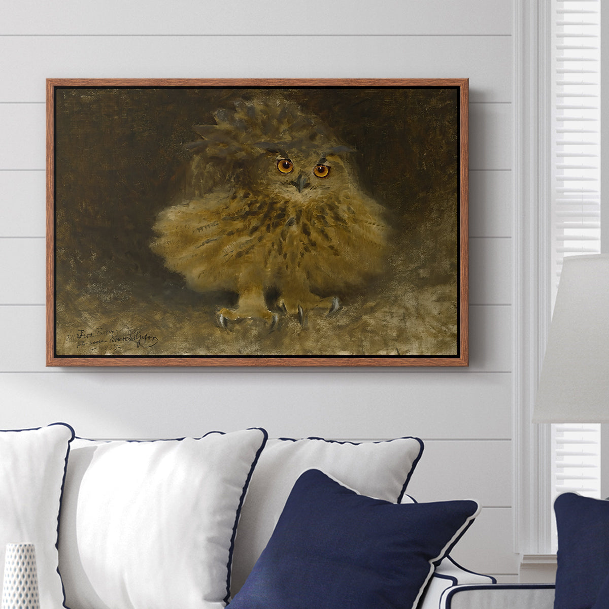 An Eagle Owl (Berguv), 1905 by Bruno Liljefors displayed above a sofa in a living room in a walnut floater frame, featuring a detailed wildlife painting of eagle owl with piercing eyes in darkness.