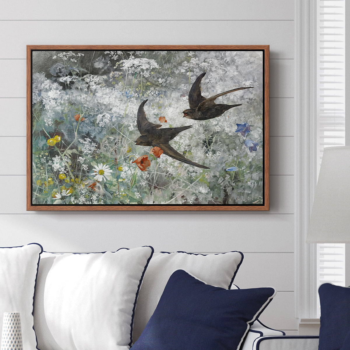 Common Swifts, 1886 by Bruno Liljefors displayed above a sofa in a living room in a walnut floater frame, featuring swifts gliding midair with wings spread against soft sky.