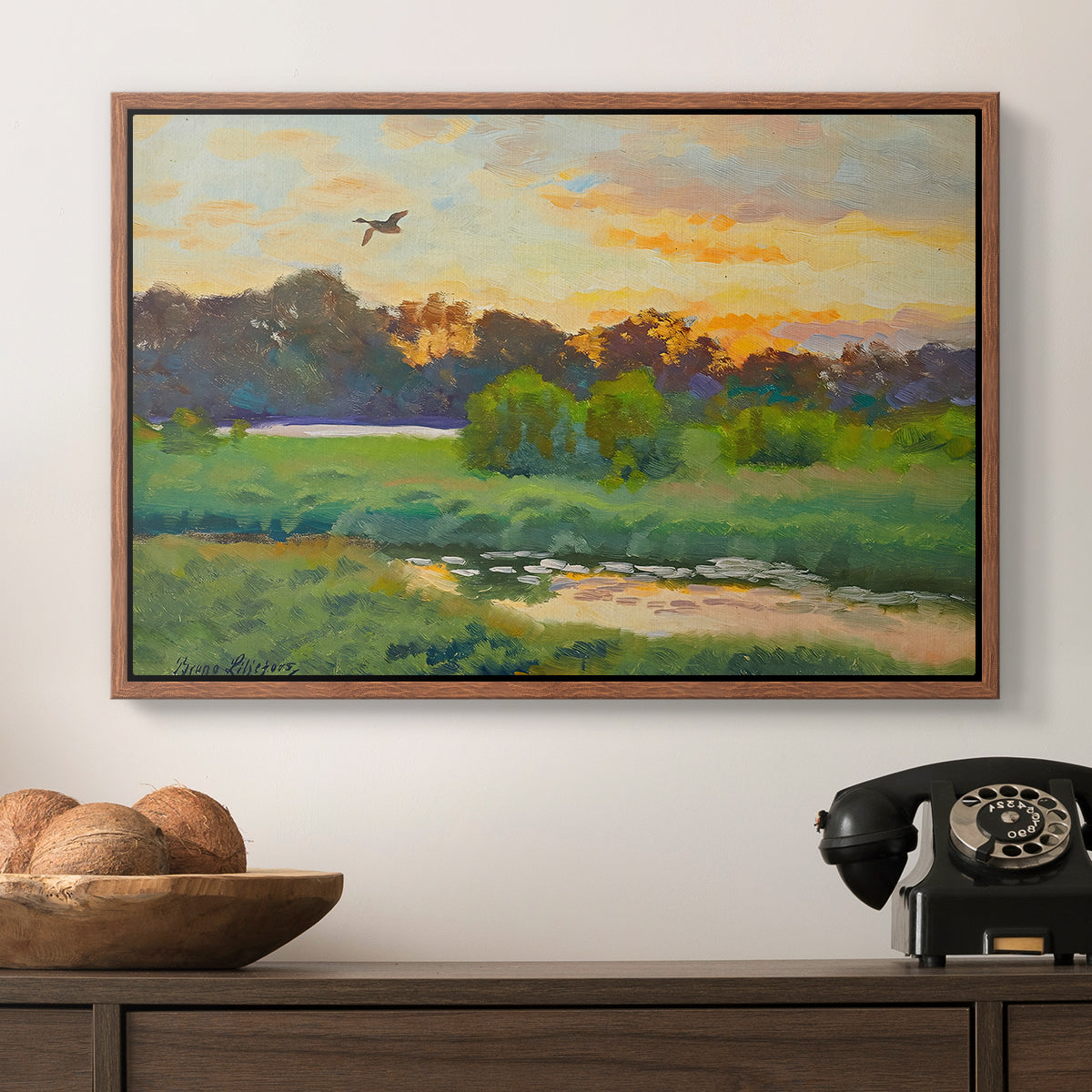 Flying Duck at Sunset, 1924 by Bruno Liljefors in a walnut floater framed canvas displayed above a console table in a hallway, featuring a lone duck flying over a marsh at golden hour.