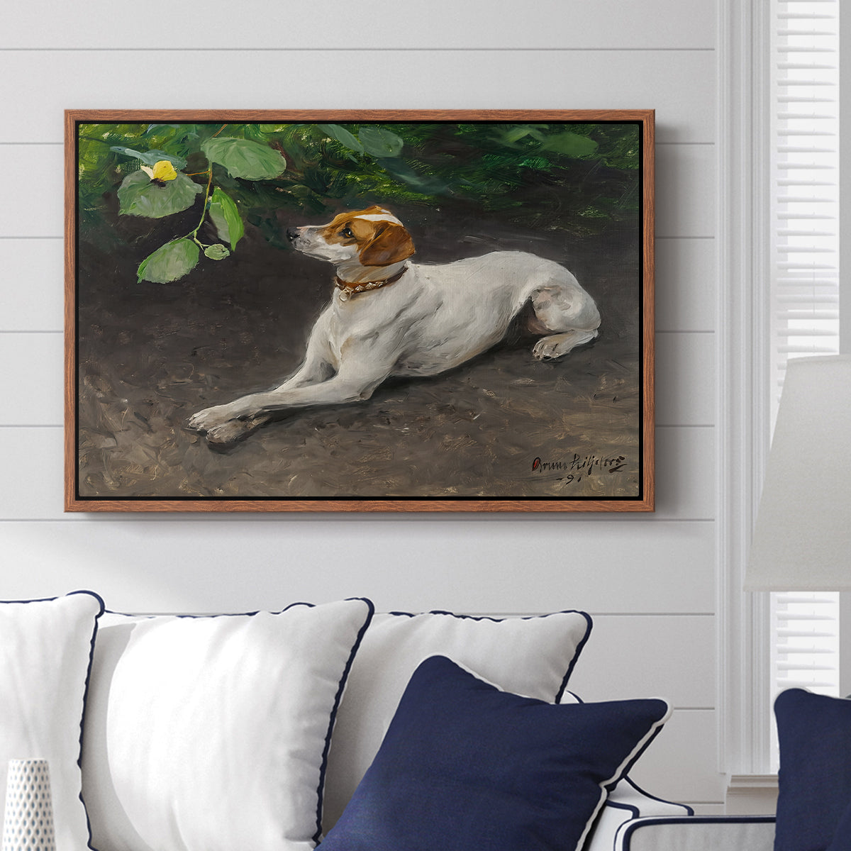 Portrait of a Dog, 1891 by Bruno Liljefors displayed above a sofa in a living room in a walnut floater frame, featuring a realistic portrait of a resting dog with attentive expression.
